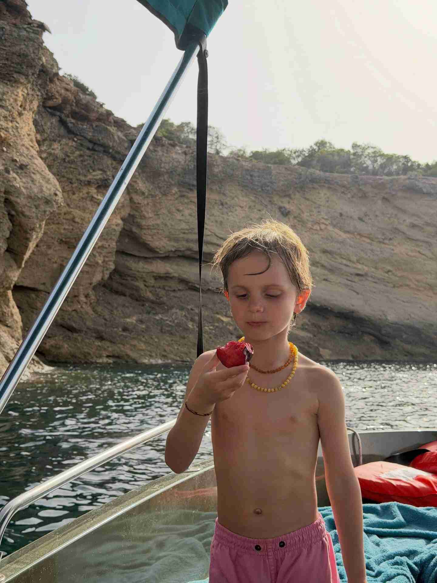 Niño pequeño sosteniendo una fruta en un barco en Ibiza